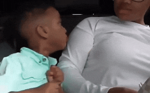 a little boy is kissing a woman 's cheek while sitting in a car