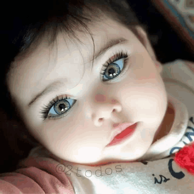 a baby with blue eyes is wearing a shirt that says unicorn on it