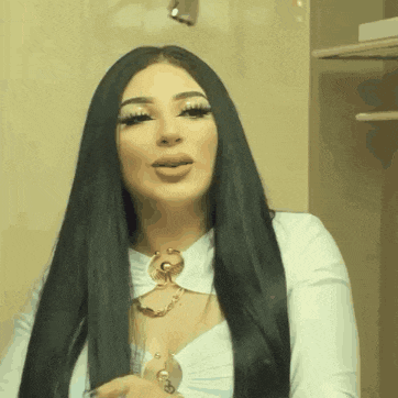 a woman with long black hair is wearing a white shirt and a necklace