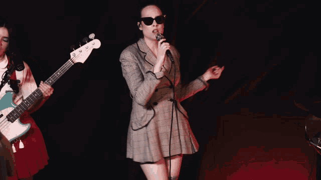 a woman is singing into a microphone while a man plays a guitar
