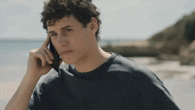 a man with curly hair is talking on a cellphone