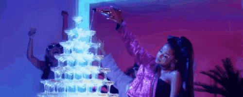 a woman is pouring a bottle of champagne into a pyramid of champagne glasses .
