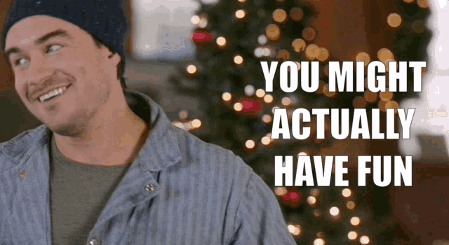 a man is smiling in front of a christmas tree with the words you might actually have fun above him