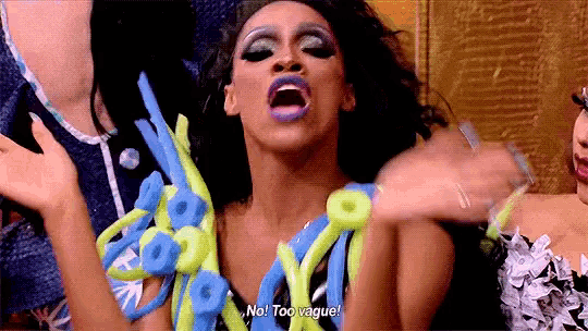 a drag queen says " no too vague " while holding balloons in her hands
