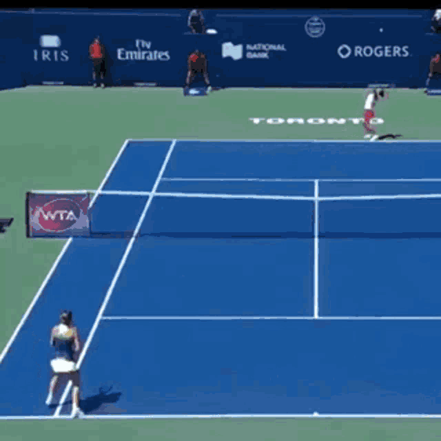 a woman playing tennis in front of a rolex banner