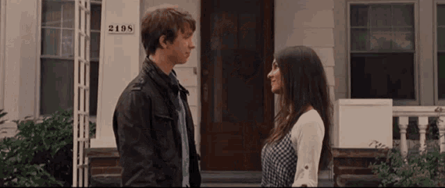 a man and woman are standing in front of a house with the number 2108