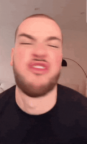 a man with a beard is making a funny face with his mouth open .