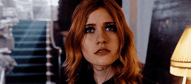 a close up of a woman 's face with red hair and freckles looking at the camera .