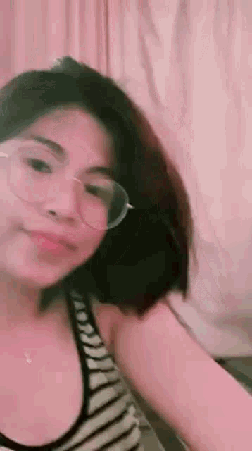 a woman wearing glasses and a striped shirt is taking a selfie .