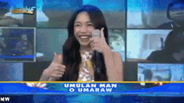 a woman giving a thumbs up in front of a sign that says ' umulan man o umaraw '