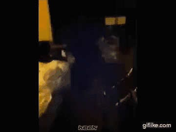 a man is smoking a cigarette in a dark room with the word keek on the bottom right