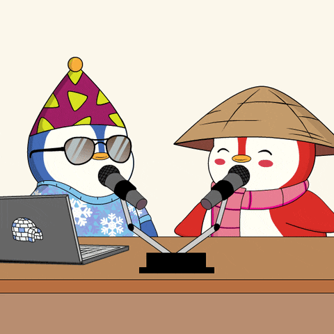 two penguins are sitting at a table with microphones