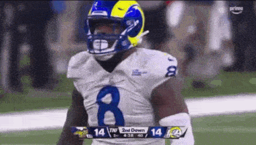 a football player wearing a helmet and number 8 jersey is standing on a field .