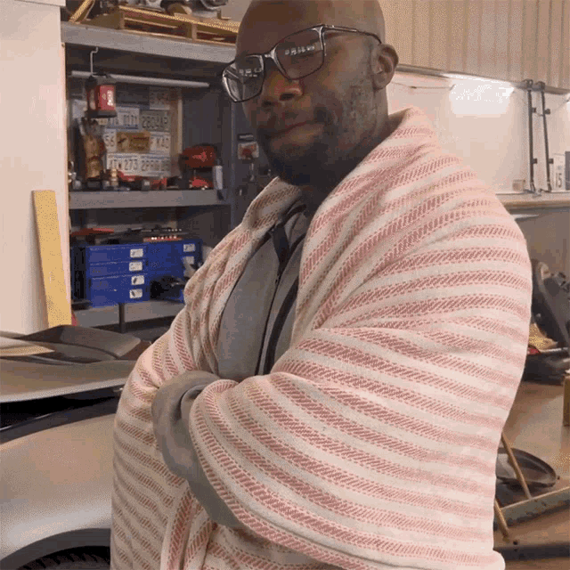 a man wearing glasses is wrapped in a pink and white striped towel