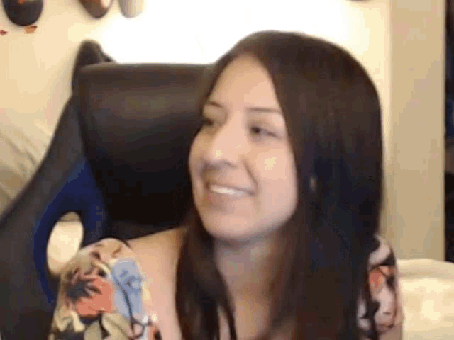 a woman is sitting in a chair and smiling while looking at the camera .