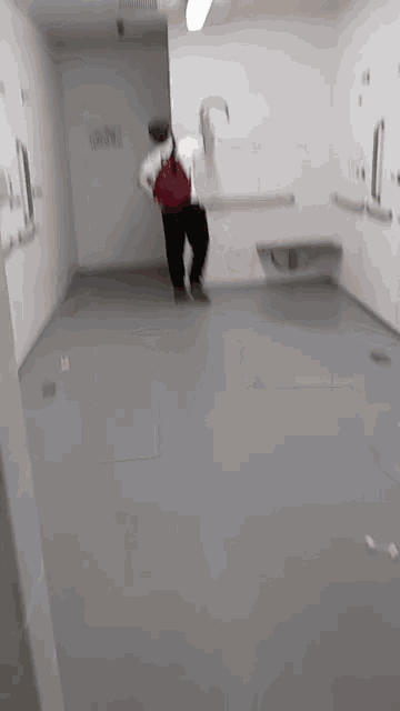 a person is standing in a room with a gray floor and a white wall .
