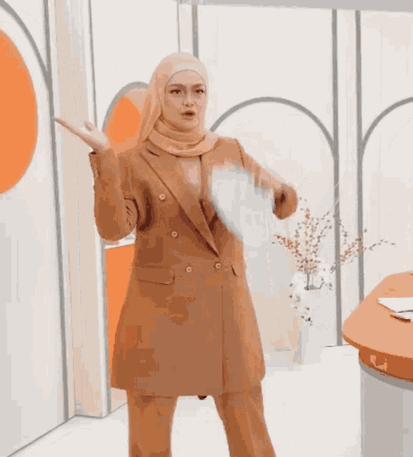 a woman wearing a hijab and a suit is dancing