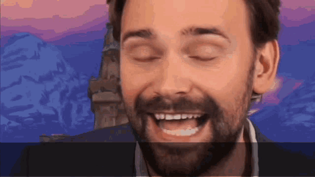 a man with a beard is smiling with his eyes closed and his mouth open