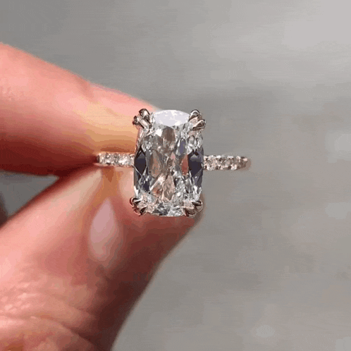 a close up of a person holding a diamond ring in their hand