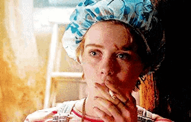 a woman wearing a bath cap is smoking a cigarette .