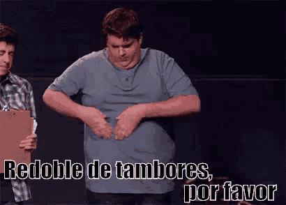 a man in a blue shirt is holding his stomach and says redoble de tambores