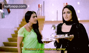 two women are standing next to each other and one of them is holding a tray .