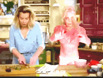 a woman in a blue shirt is cutting vegetables in a kitchen