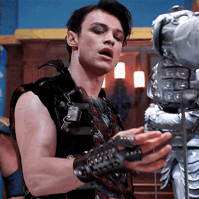 a young man in a costume is holding a sword in his hand .