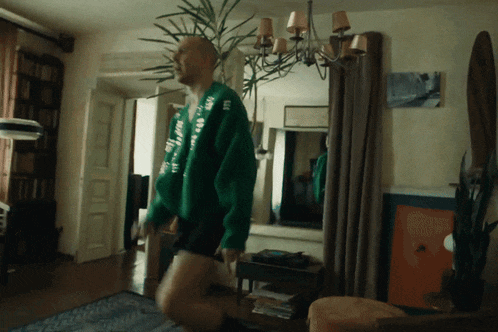 a man in a green sweater that says ' i love you ' on it is standing in a living room