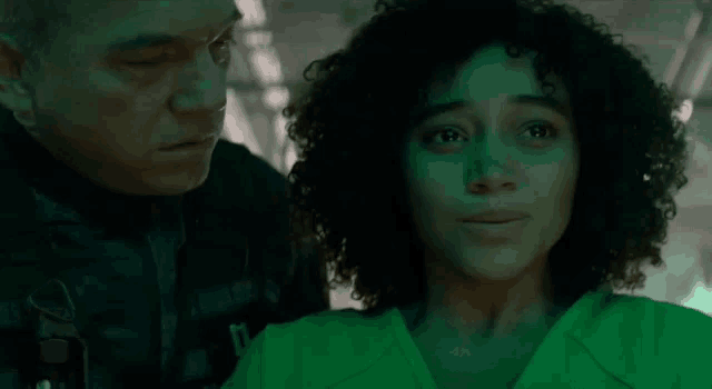 a man and a woman are standing next to each other in a dark room in a green light .