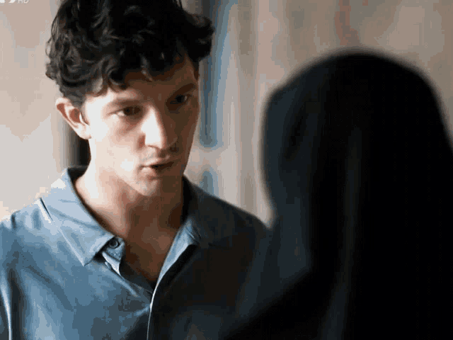 a man in a blue shirt is looking at a woman in a black veil