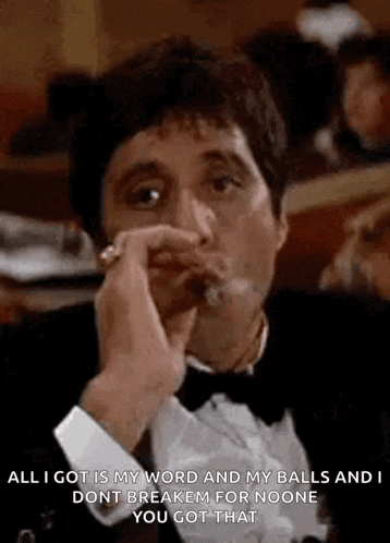 a man in a tuxedo is smoking a cigar and talking to another man .