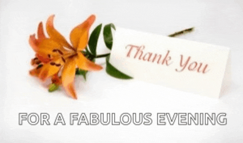 a thank you card is next to a flower on a table .