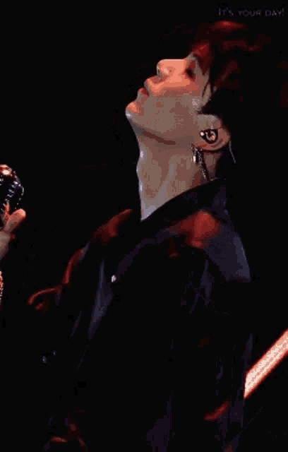 a man with red hair is wearing a red jacket and earphones while looking up .
