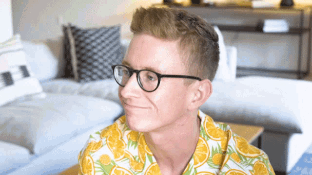a young man wearing glasses and a yellow shirt with oranges on it