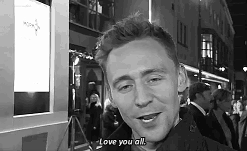 a man is smiling and saying `` love you all '' while standing in front of a crowd of people .