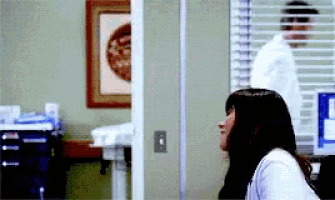 a woman is looking out a window while a man in a lab coat stands behind her