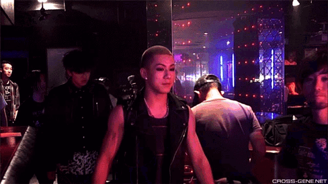 a group of people are standing in a dark room with the words cross-gene.net in the bottom right corner