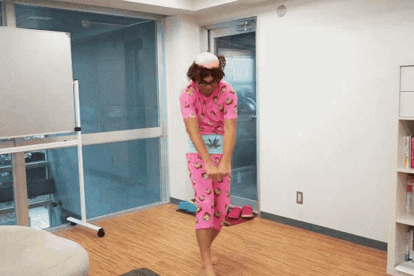 a man in a pink pajama set is standing in front of a window
