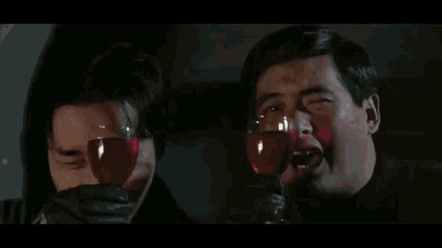 two men are standing next to each other and smiling while holding glasses of wine .