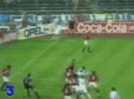a blurry picture of soccer players on a field with a coca cola ad in the background