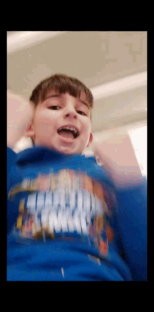 a young boy wearing a blue shirt that says ' avengers ' on it