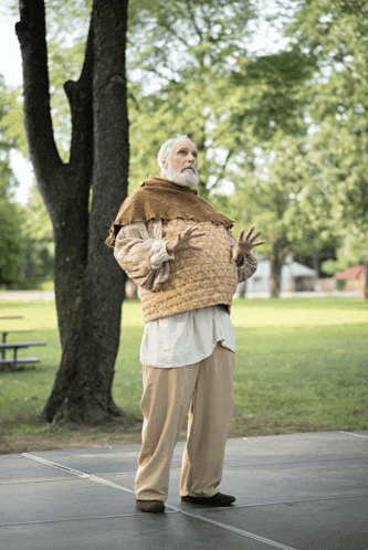 a man with a beard is standing in a park