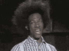 a man with an afro is giving the ok sign .