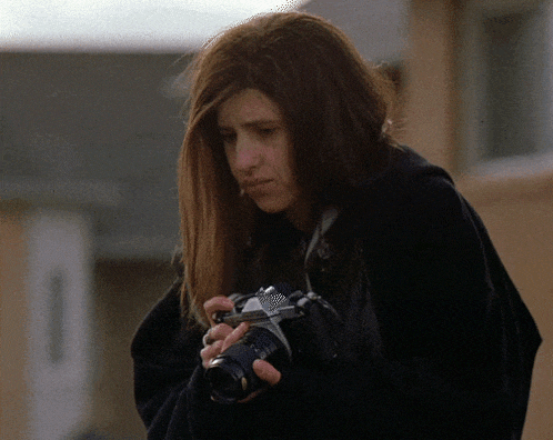 a woman is holding a camera in her hand and looking down