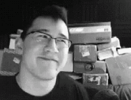 a man wearing glasses is smiling in front of a pile of books