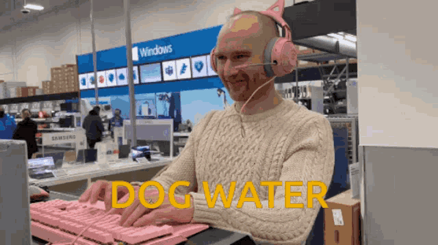 a bald man wearing pink headphones is typing on a pink keyboard with the words dog water above him