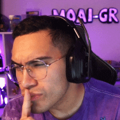 a man wearing headphones holds his finger to his lips in front of a moai-gr sign