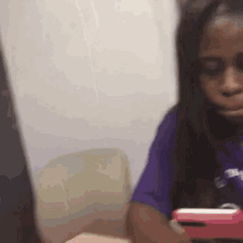a woman in a purple shirt is looking at her phone .