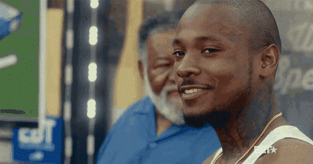 a man with a tattoo on his arm is smiling in front of a sign that says j.p.